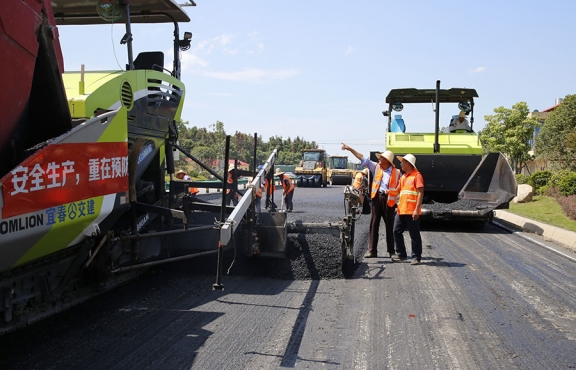 攤鋪機(jī)、壓路機(jī)等設(shè)備緊張有序運(yùn)行，高達(dá)170℃的瀝青混合料炙烤著公路人
